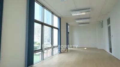 Spacious empty room with large windows and city view, ideal for office or studio space.