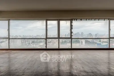 Spacious room with panoramic city view through large windows, ideal for urban living.