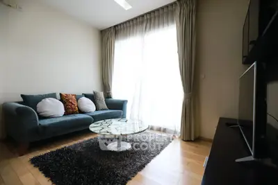 Modern living room with stylish sofa, elegant curtains, and sleek TV setup.