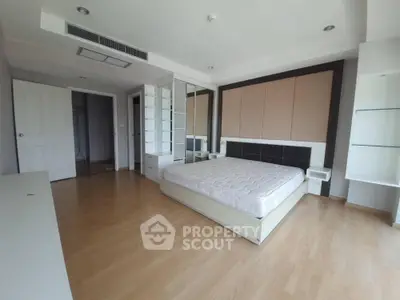 Spacious bedroom with modern design and ample natural light, featuring a stylish bed and sleek wooden flooring.