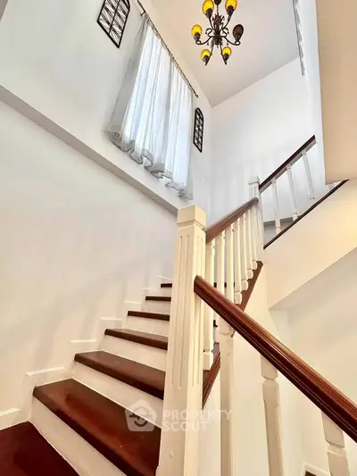Elegant staircase with wooden steps and chandelier in a bright home interior