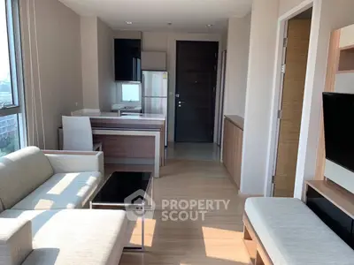 Modern living room with open kitchen, sleek furniture, and natural light in a stylish apartment.