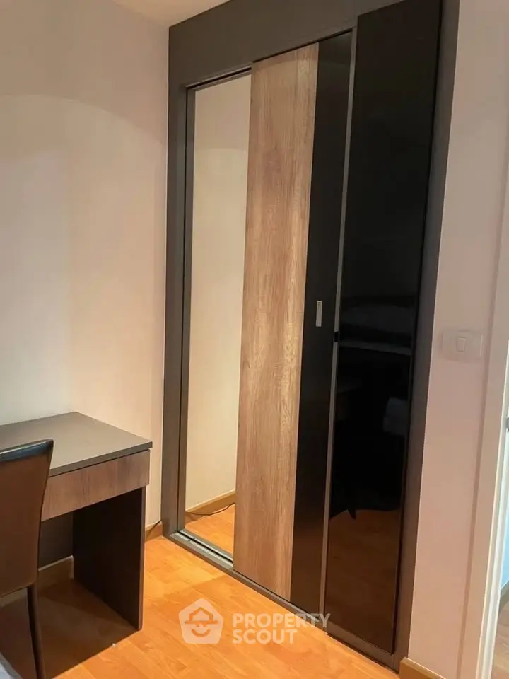 Modern bedroom with sleek sliding wardrobe and compact desk setup.