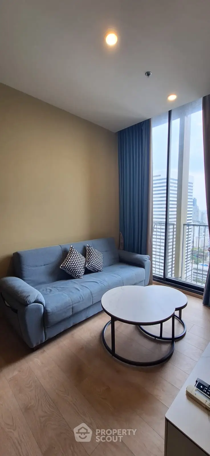 Modern living room with city view, featuring a stylish sofa and coffee table.