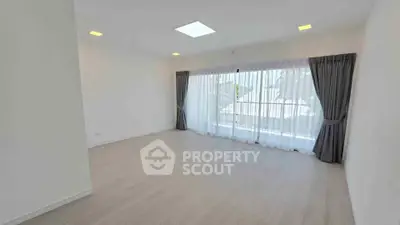 Spacious and bright living room with large windows and elegant curtains