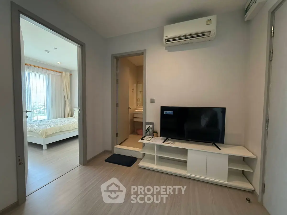 Modern apartment interior with bedroom and living area featuring air conditioning and sleek TV setup.