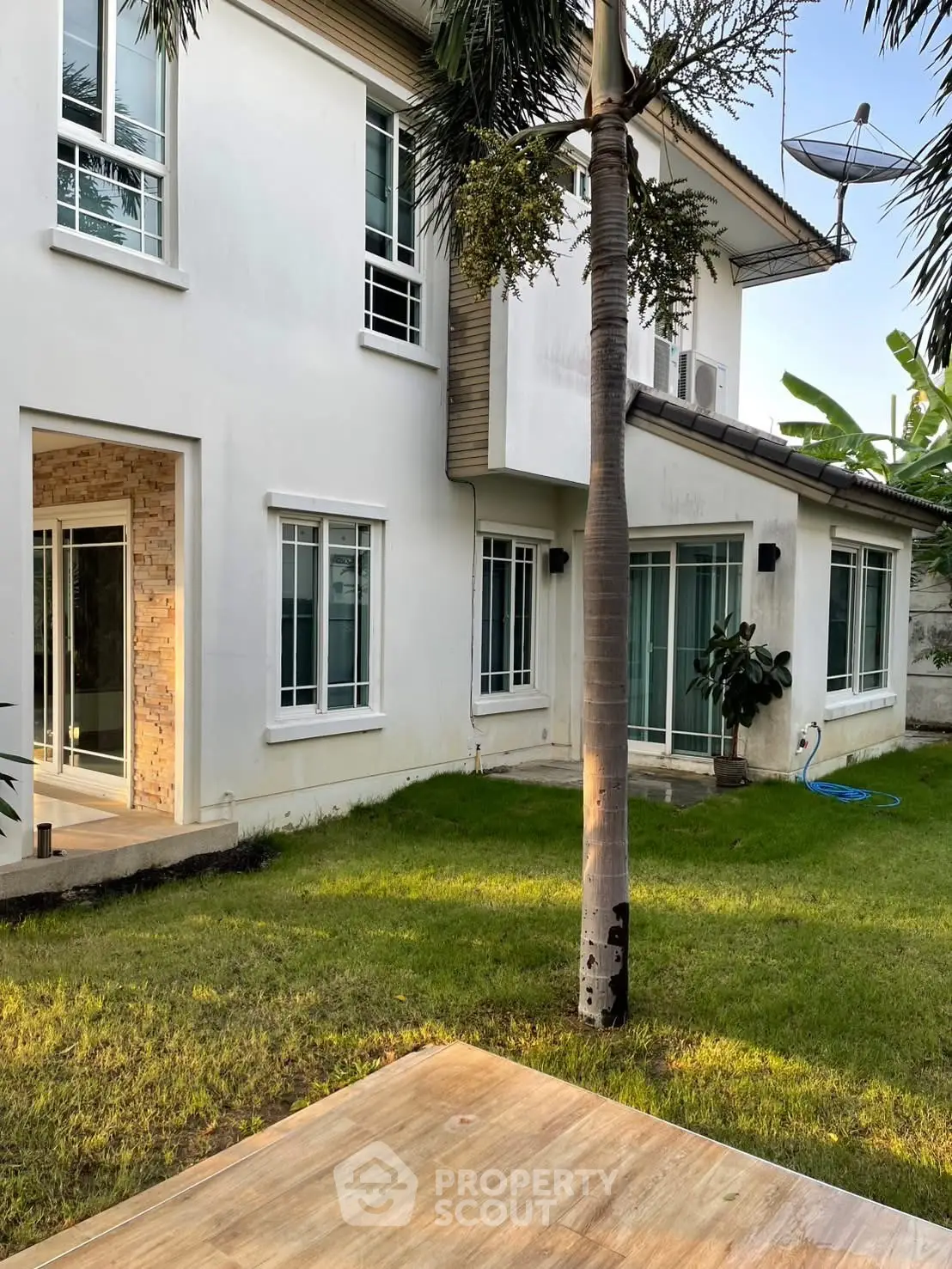 Charming two-story house with lush green garden and modern exterior design.