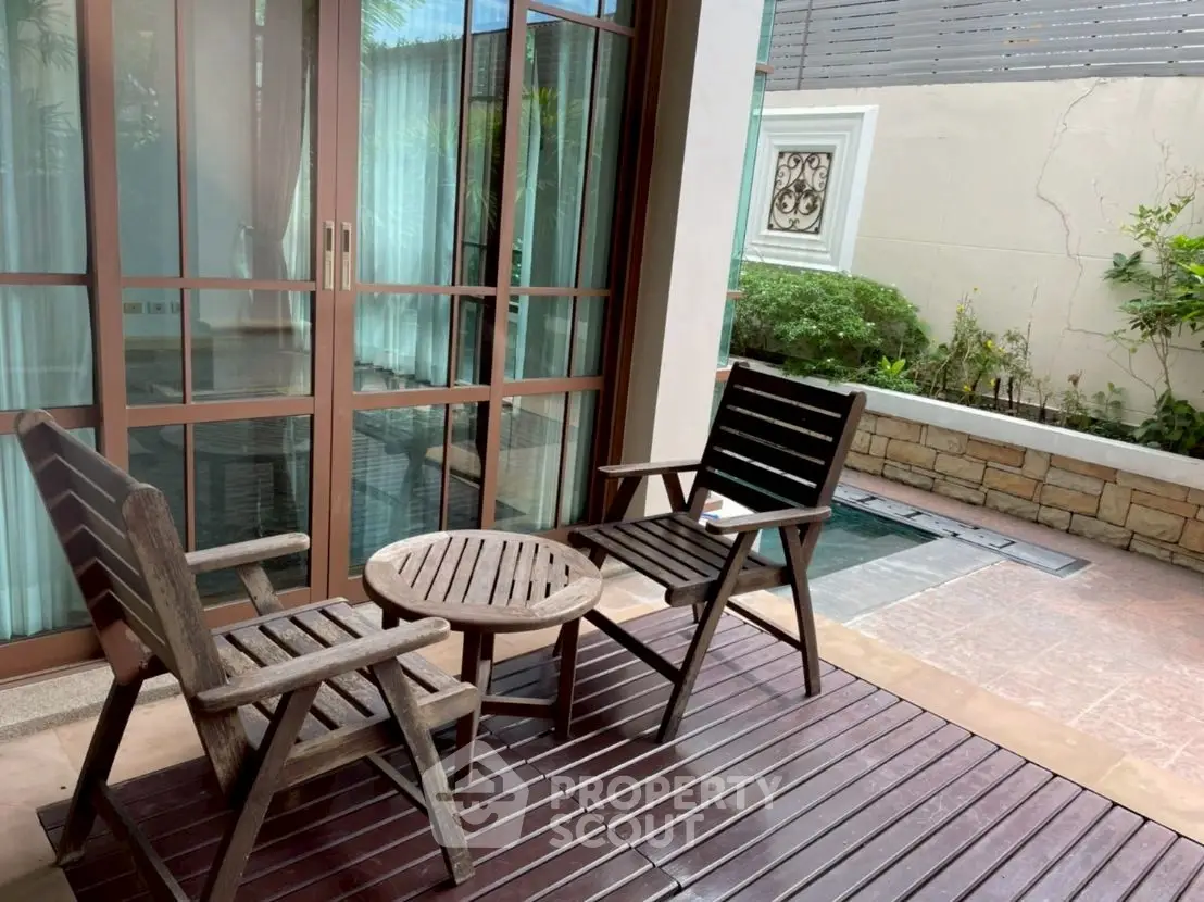Charming patio with wooden furniture and small garden view, perfect for relaxation.