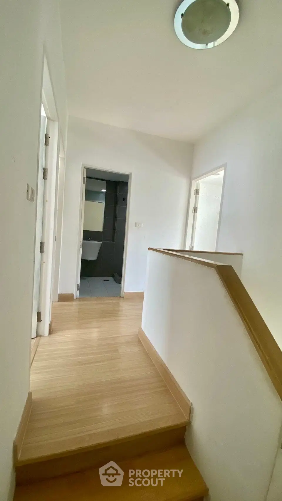 Bright hallway with wooden flooring leading to multiple rooms in a modern home.
