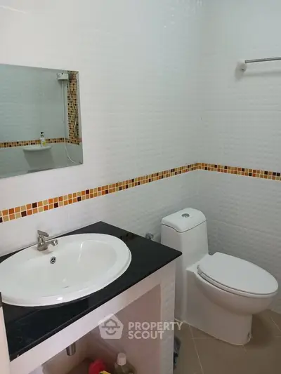 Modern bathroom with sleek sink and toilet, featuring stylish tile accents.