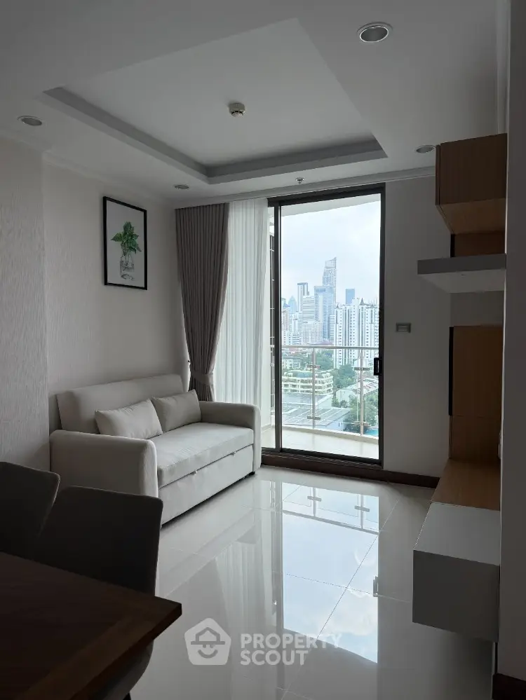 Modern living room with city view, sleek furniture, and large window in high-rise apartment.
