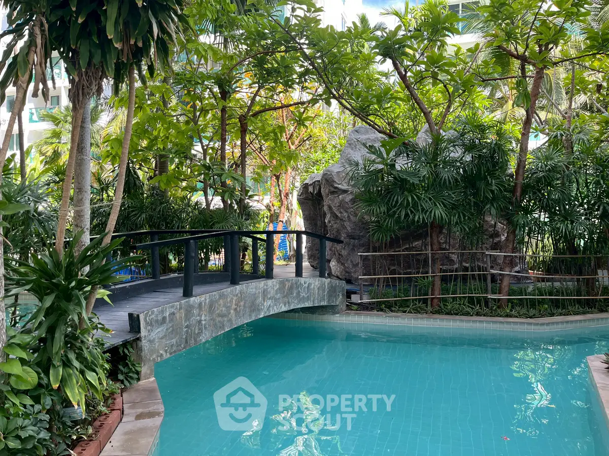 Luxurious tropical pool area with lush greenery and serene bridge, perfect for relaxation and leisure.
