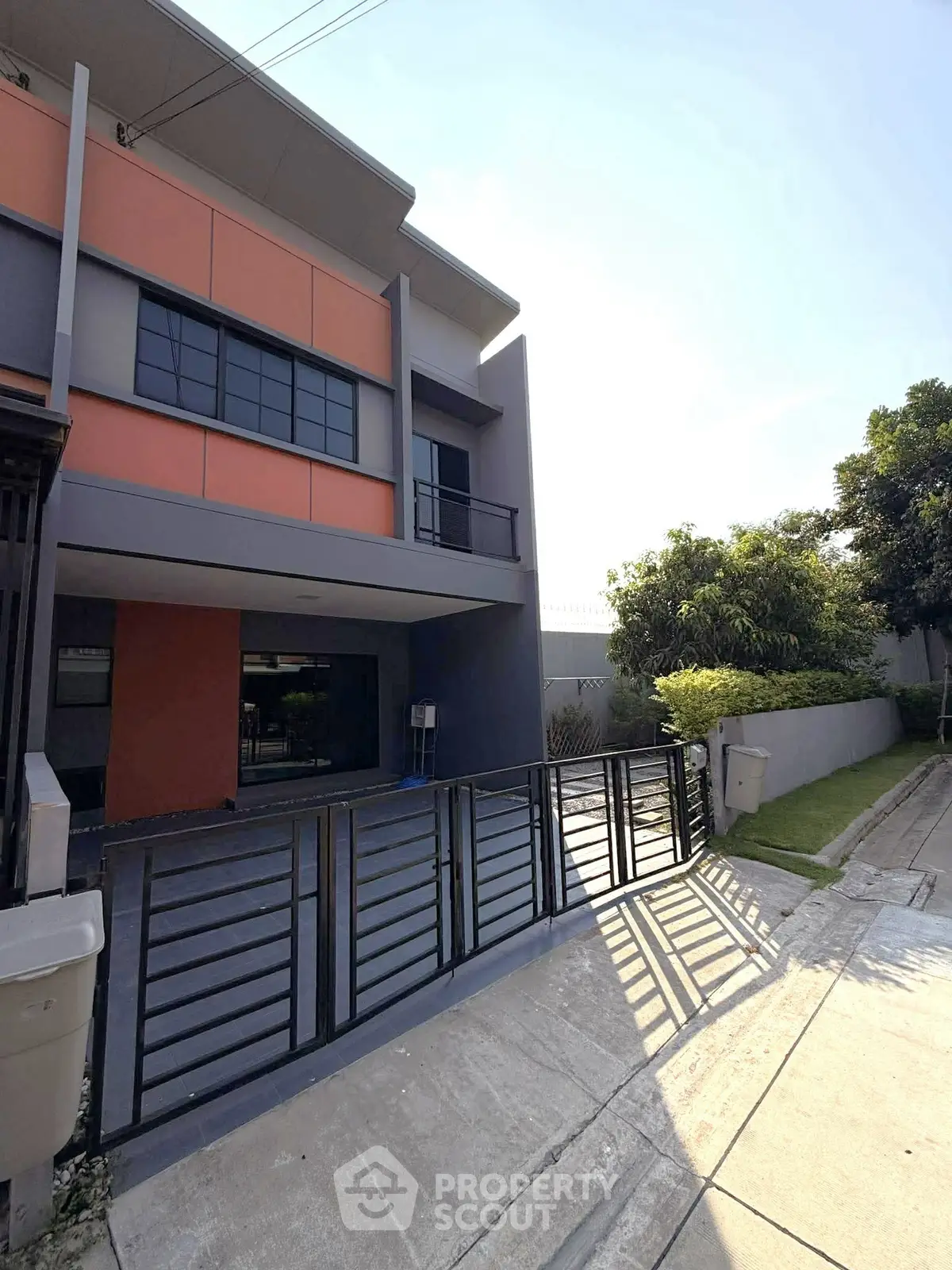 Modern two-story house with sleek design and gated driveway in a suburban neighborhood.
