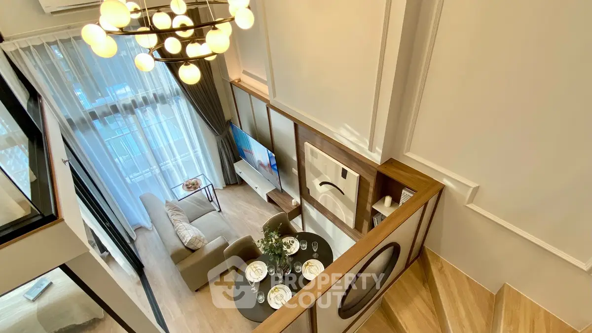 Modern living room with high ceiling and elegant chandelier, featuring cozy seating and stylish decor.