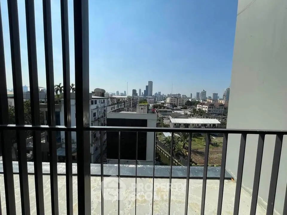 Stunning cityscape view from a high-rise balcony with clear blue skies.