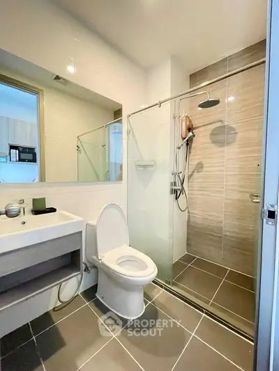 Modern bathroom with glass shower and sleek fixtures in contemporary apartment.
