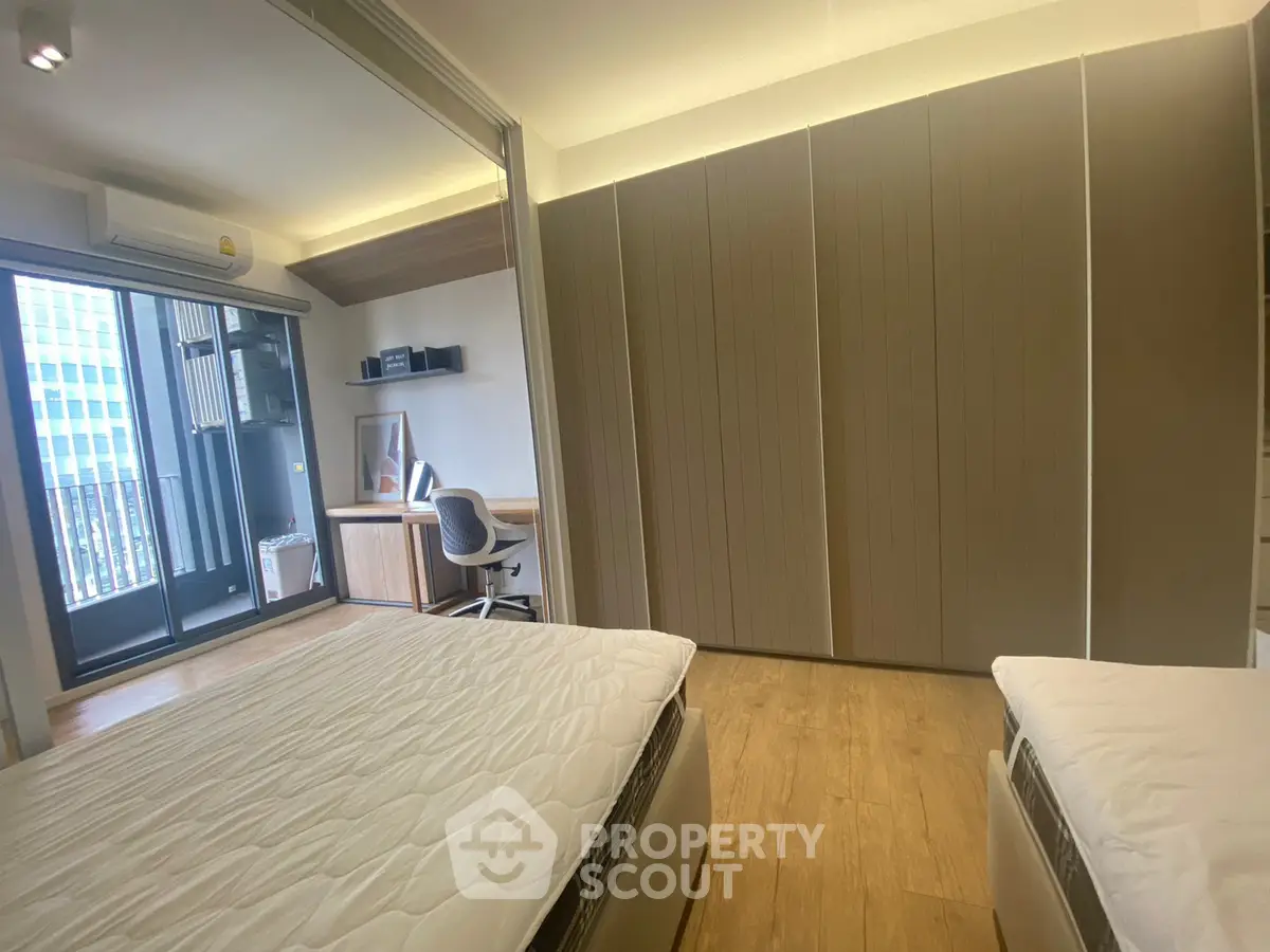 Modern bedroom with balcony access and study area, featuring sleek design and ample natural light.