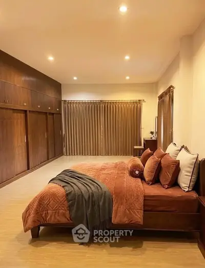 Spacious bedroom with elegant wooden accents and cozy bedding in a modern home.
