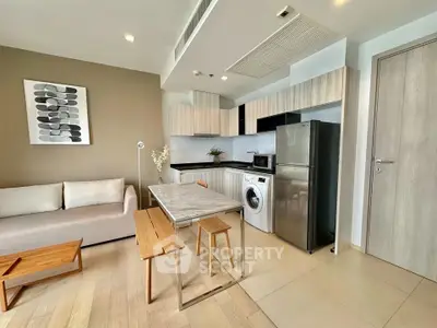 Modern open-plan living room with kitchen, featuring sleek appliances and stylish decor.