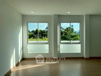 Bright and spacious room with large windows offering a serene garden view, perfect for a tranquil living space.