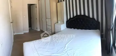 Spacious bedroom with elegant headboard and striped accent wall in modern apartment.