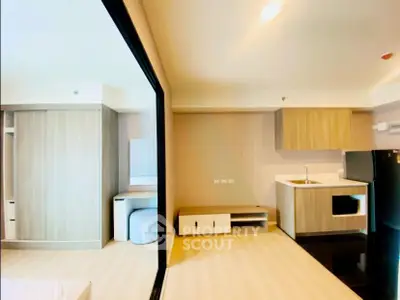 Modern open-layout studio apartment with sleek kitchen and ample storage space.