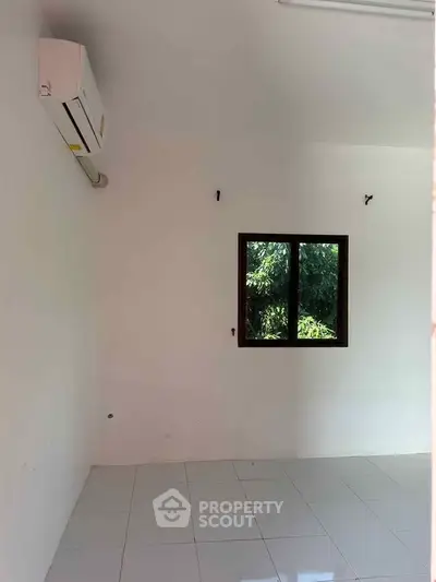 Bright empty room with air conditioning and window view of greenery, perfect for customization.