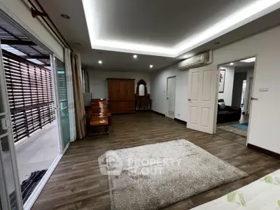 Spacious living room with modern lighting, large windows, and wooden flooring, perfect for family gatherings and relaxation.
