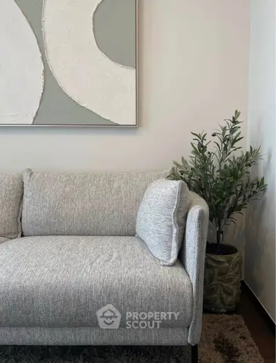 Modern living room with stylish gray sofa and abstract wall art