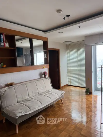 Spacious living room with parquet flooring and balcony access in modern apartment.