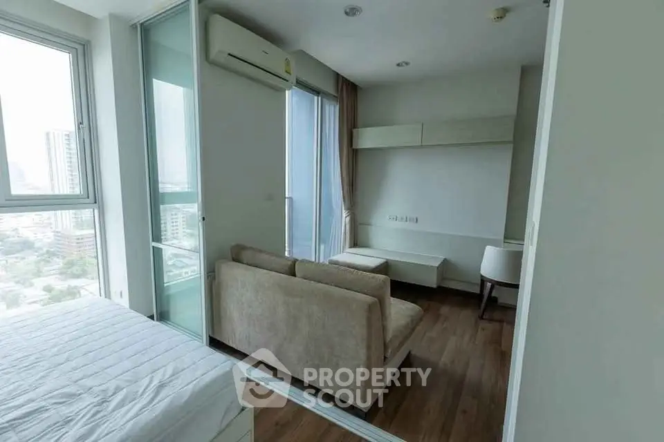 Modern apartment interior with cozy living area and large windows offering city views.