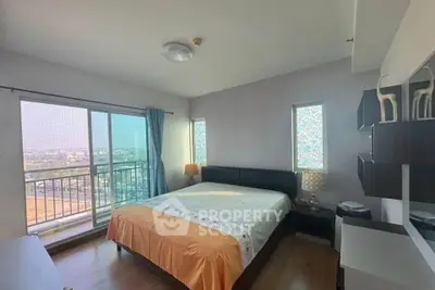 Spacious bedroom with large windows and balcony access offering stunning city views.