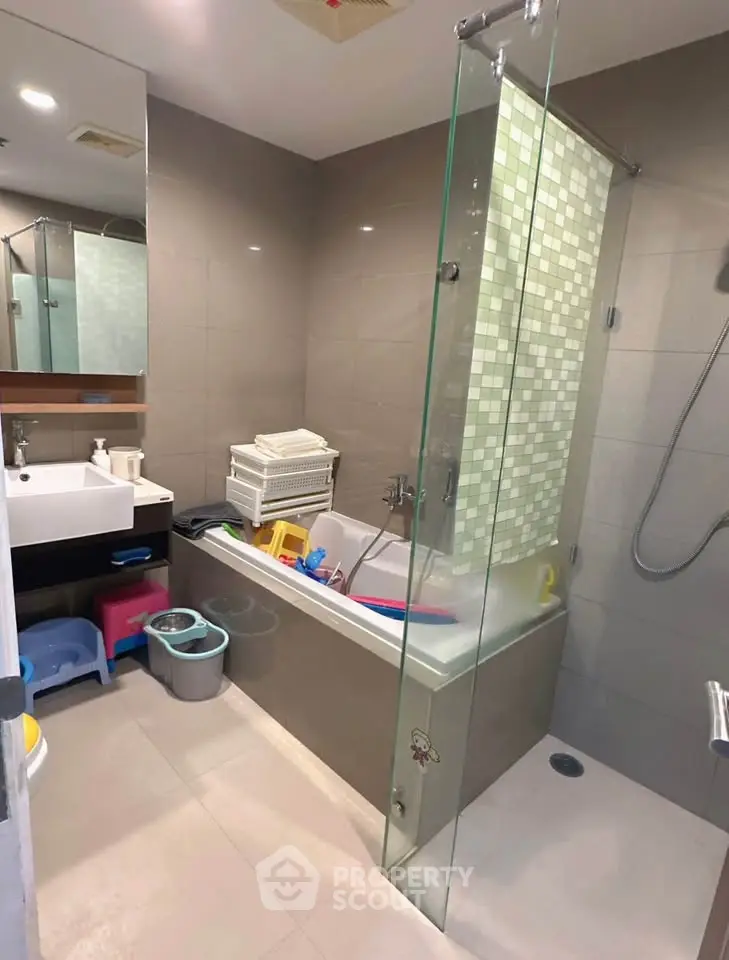 Modern bathroom with bathtub and glass shower partition in stylish apartment.