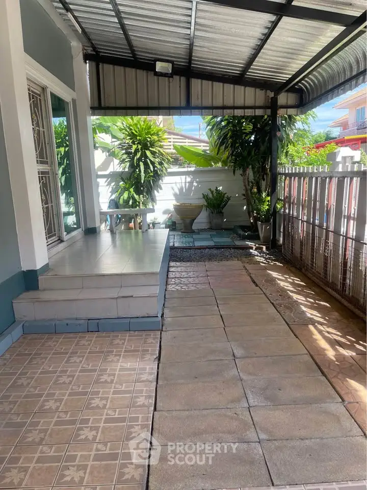 Charming covered patio with tiled flooring and lush greenery, perfect for relaxation and outdoor gatherings.