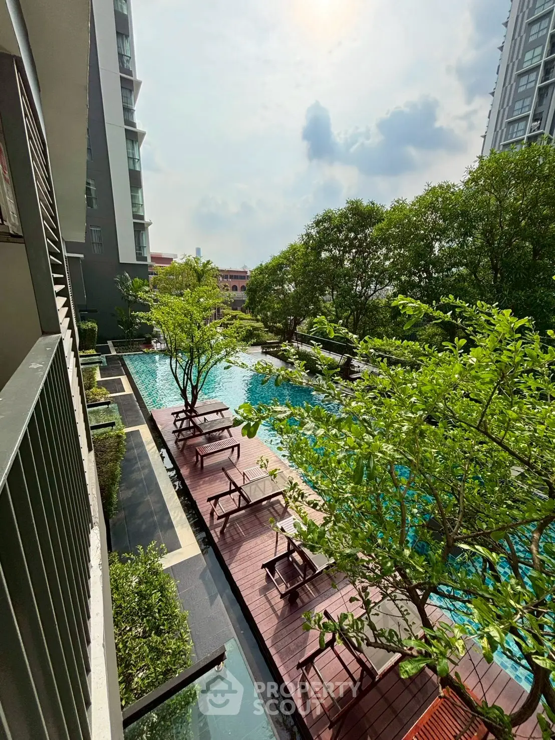 Luxurious condominium pool area with lush greenery and modern design.