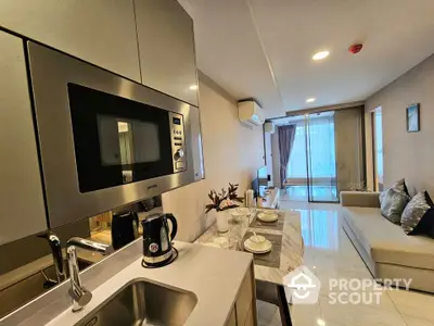 Modern open-layout kitchen and living room with sleek appliances and cozy seating area.