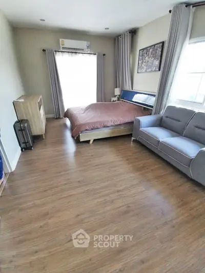 Spacious bedroom with wooden flooring and modern furnishings