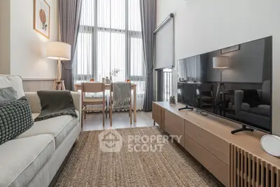 Modern living room with stylish decor and large windows, featuring a cozy sofa and sleek TV setup.