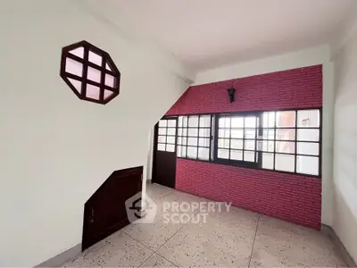 Charming interior space with unique window design and brick accent wall, perfect for creative home styling.