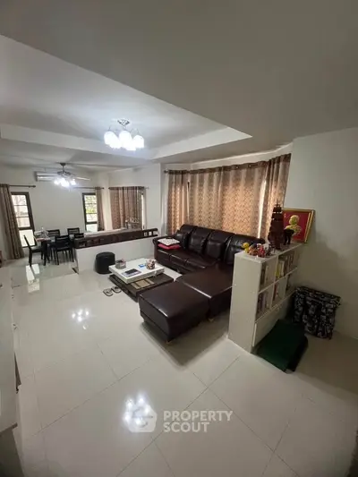 Spacious living room with modern furniture and dining area in open layout apartment.
