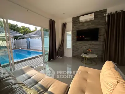 Luxurious living room with pool view, modern decor, and ample natural light.