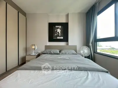 Modern bedroom with stylish decor and large window offering natural light.