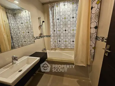Modern bathroom with stylish tiles and bathtub, featuring a sleek sink and contemporary shower setup.