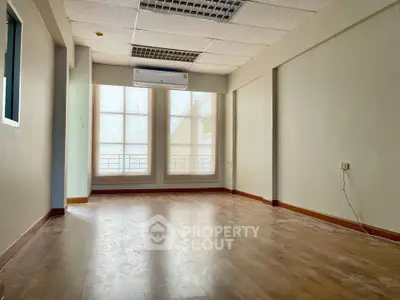 Spacious empty room with large windows and wooden flooring, ideal for customization.