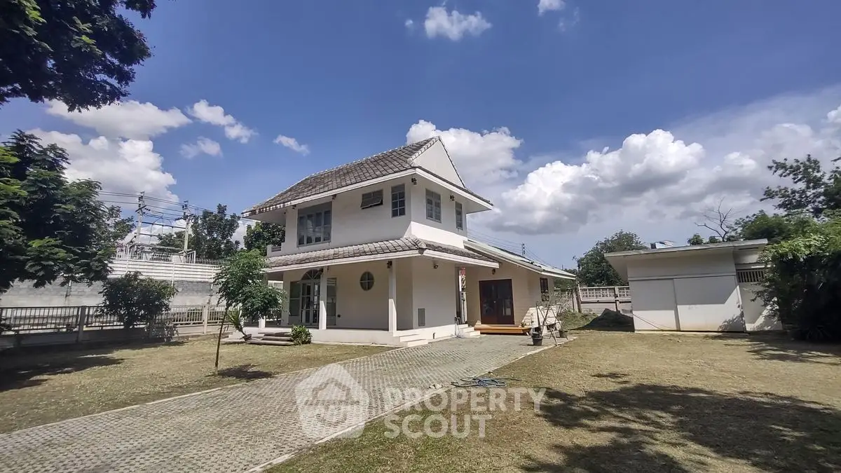 Charming two-story house with spacious garden under a clear blue sky, perfect for family living.