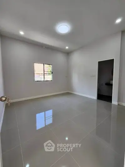 Spacious empty room with glossy tiled floor and high ceiling, perfect for customization.