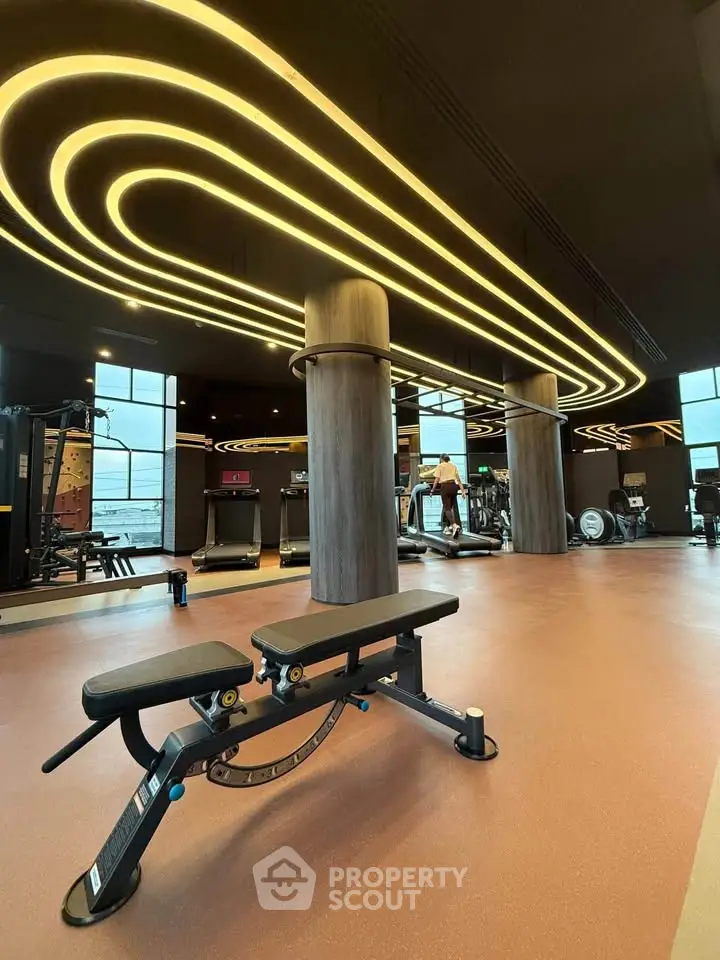 Luxurious gym with modern equipment and stylish lighting in upscale residential building.
