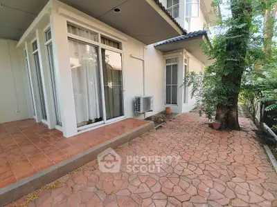 Charming exterior view of a modern home with patio and lush greenery, perfect for outdoor relaxation.