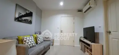 Modern living room with stylish decor, featuring a cozy sofa, air conditioning, and a sleek TV setup.