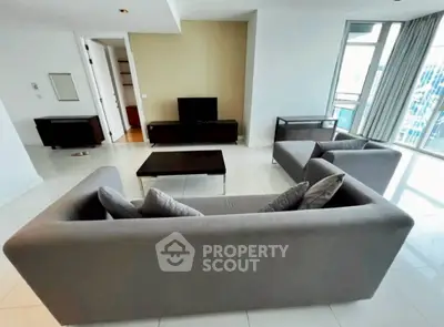 Spacious modern living room with sleek furniture and large windows offering city views.